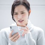 携帯を見て悩む女性