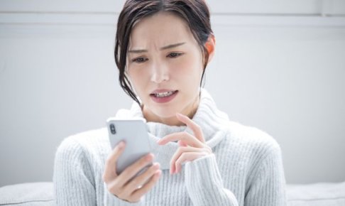 携帯を見て悩む女性