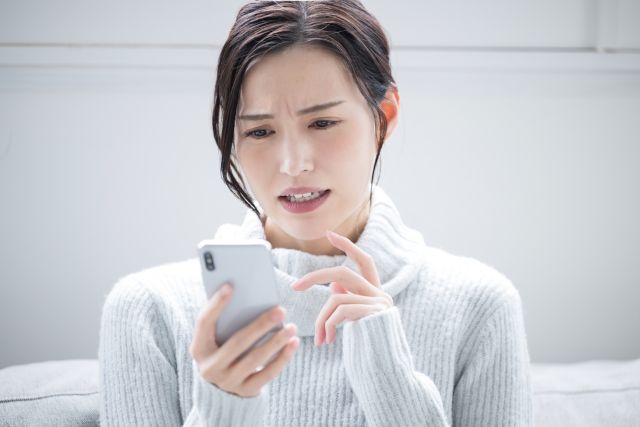 携帯を見て悩む女性