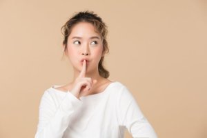 口に人差し指をあてる女性